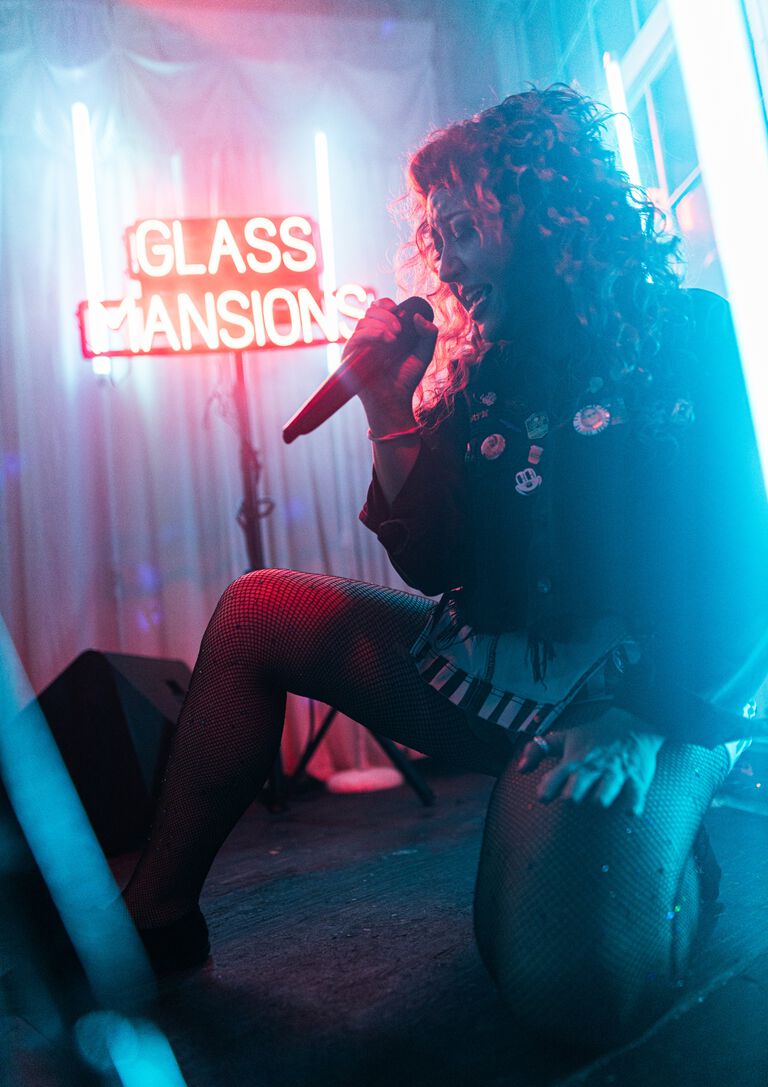 Jayna sitting and singing into a mic